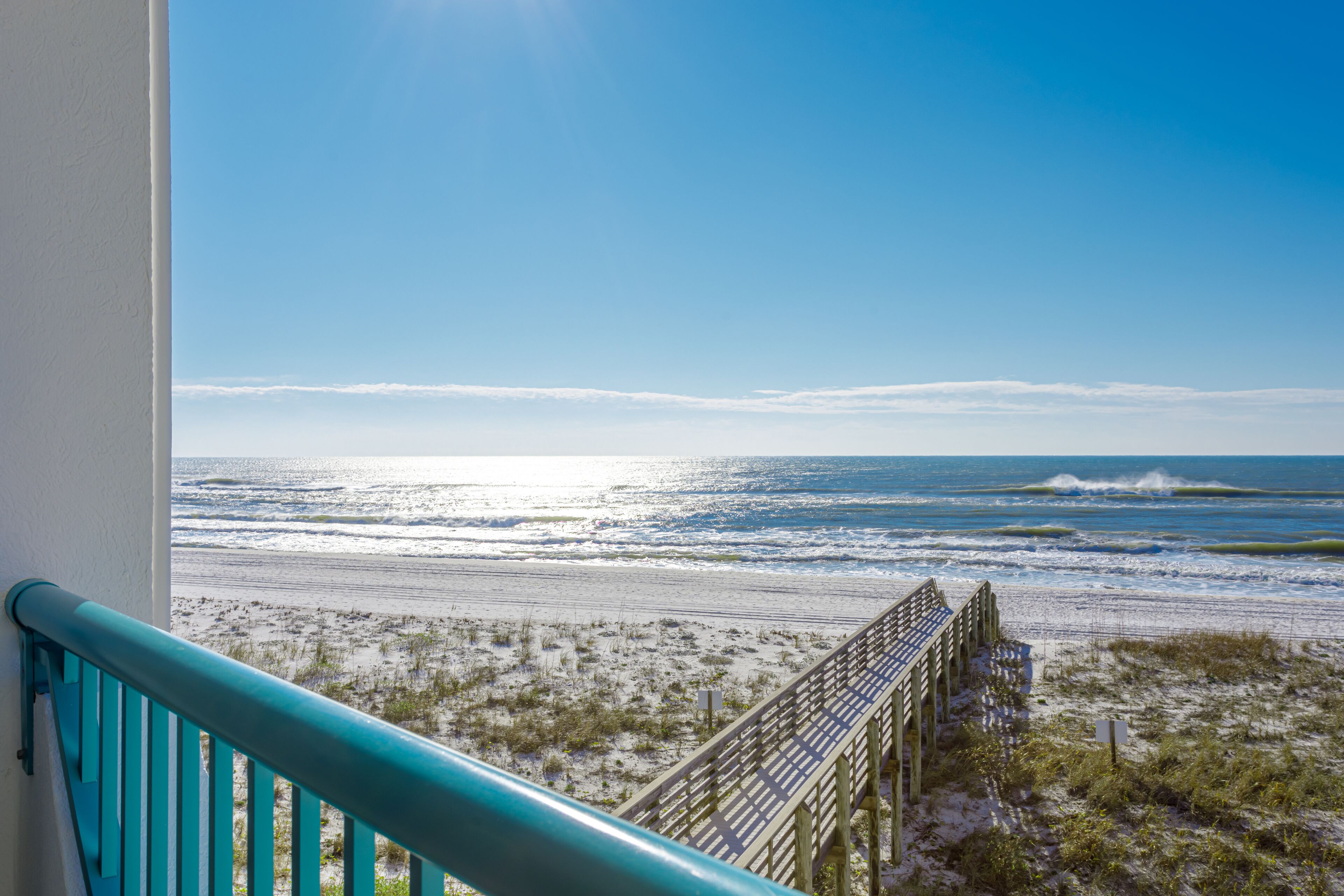 A balcony with a view of the beach and ocean.