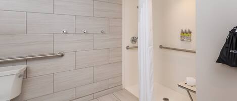 Ein modernes Badezimmer mit Dusche, Toilette und Haltegriffen.