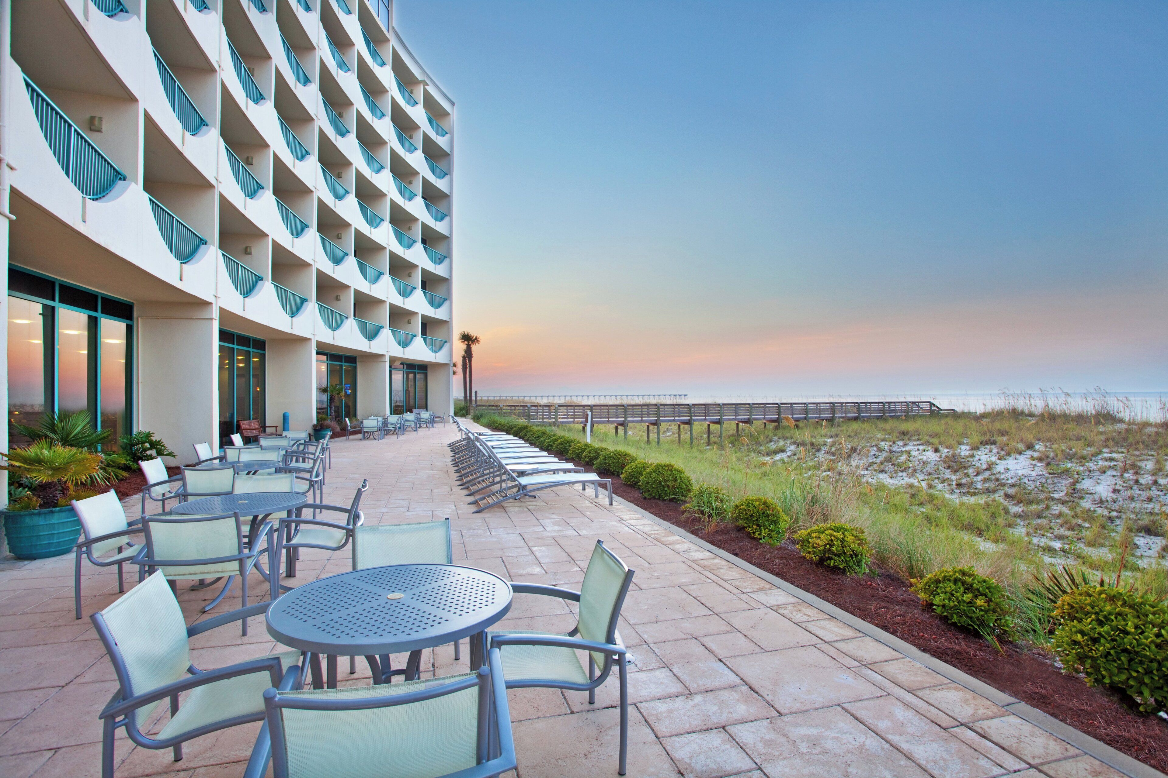 A hotel with outdoor seating and a view of the beach.