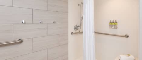 A modern bathroom with a shower, grab bars, and a towel rack.