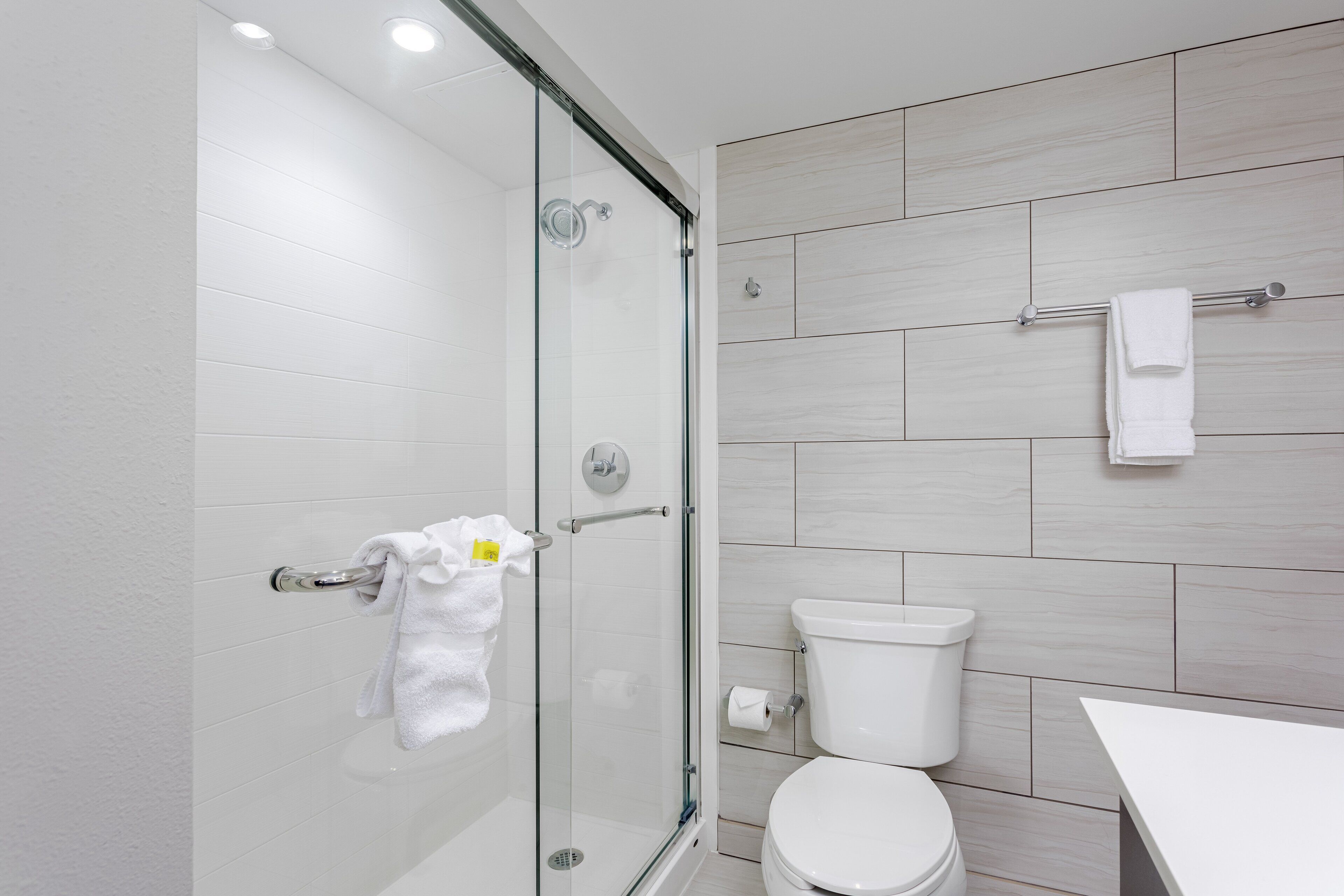 Ein modernes Badezimmer mit Duschkabine aus Glas, Toilette und weißem Waschbecken.