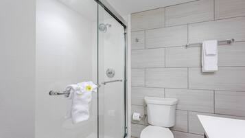 Ein modernes Badezimmer mit Duschkabine aus Glas, Toilette und weißem Waschbecken.
