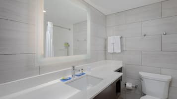 A modern bathroom with a large mirror, a sink, and a toilet.