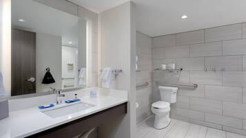 Un baño moderno con lavamanos, espejo y retrete blancos.