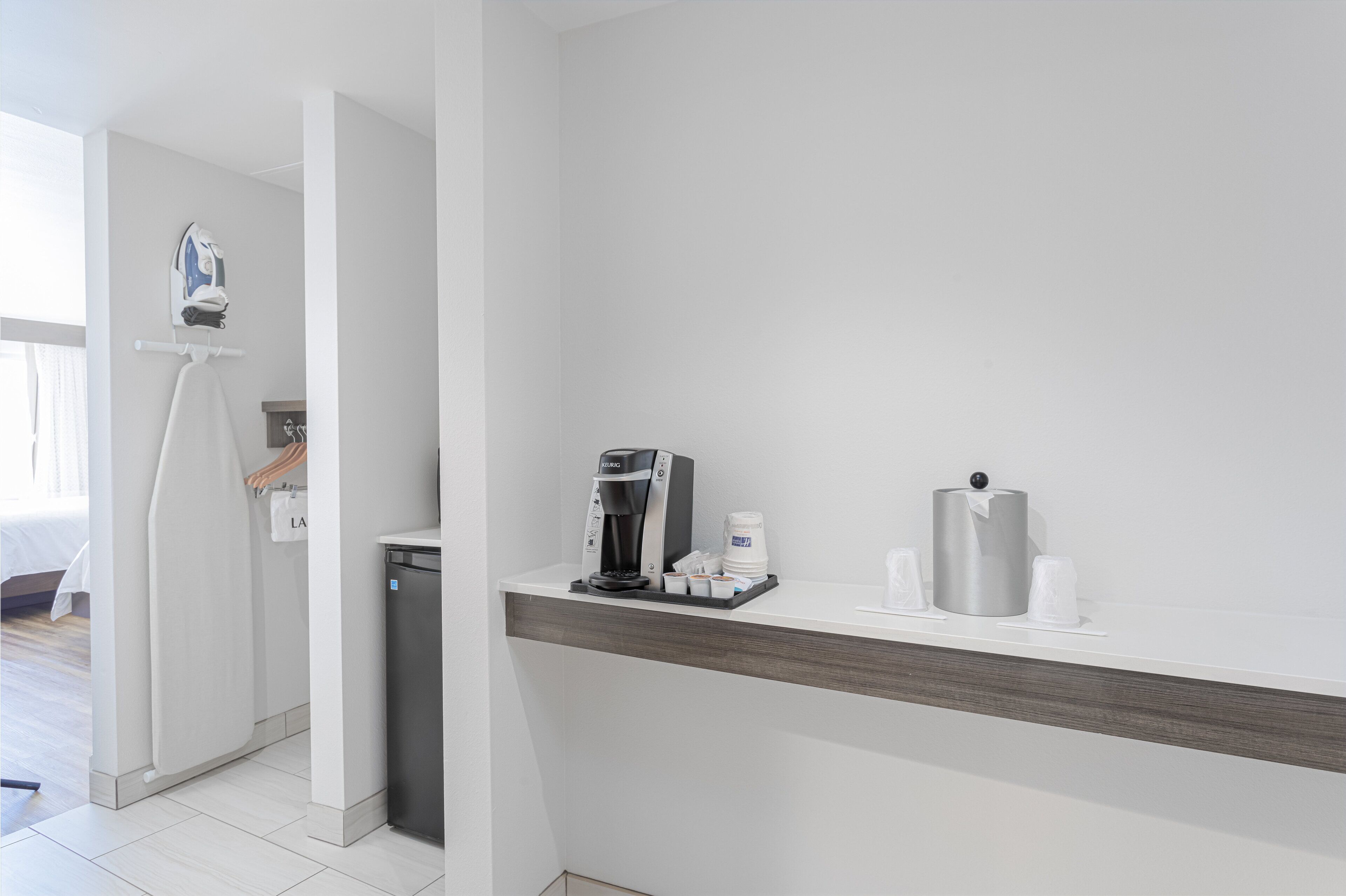 A hotel room with a coffee machine, a tissue dispenser, and a towel rack.