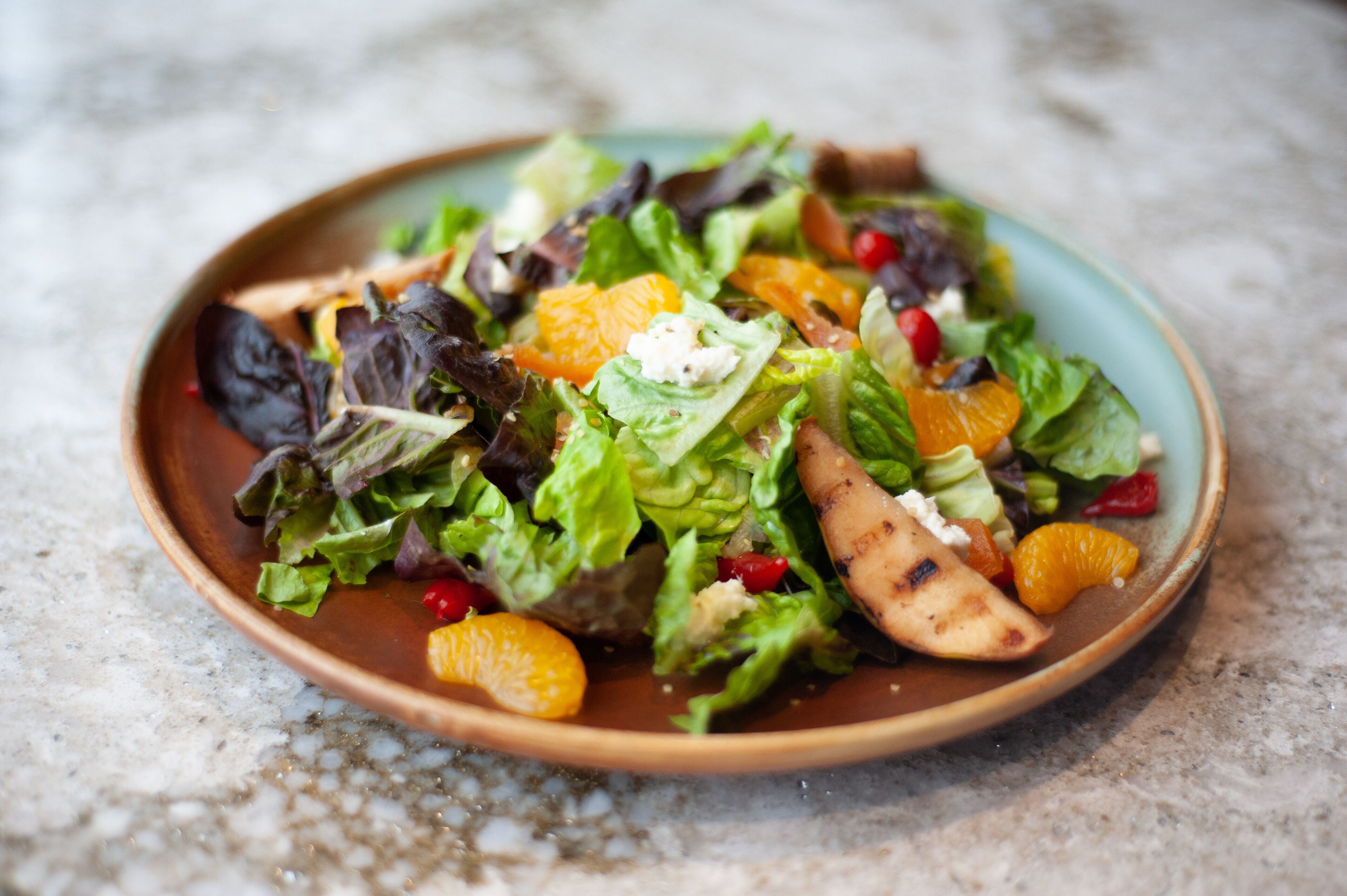 Un plato de ensalada con diferentes verduras y frutas.