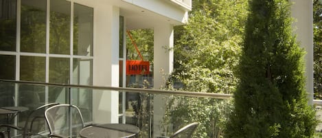 A balcony with outdoor seating, a 'HOTEL' sign, and a view of a building and trees.
