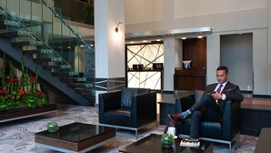 A modern lobby with a staircase, seating area, and a reception desk.