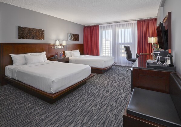 A hotel room with two beds, a desk, a chair, and a TV. - Matrix Hotel (Edmonton)