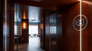 A modern interior with a glass door leading to a dining area, a visible logo on the wall, and a clean, contemporary design.