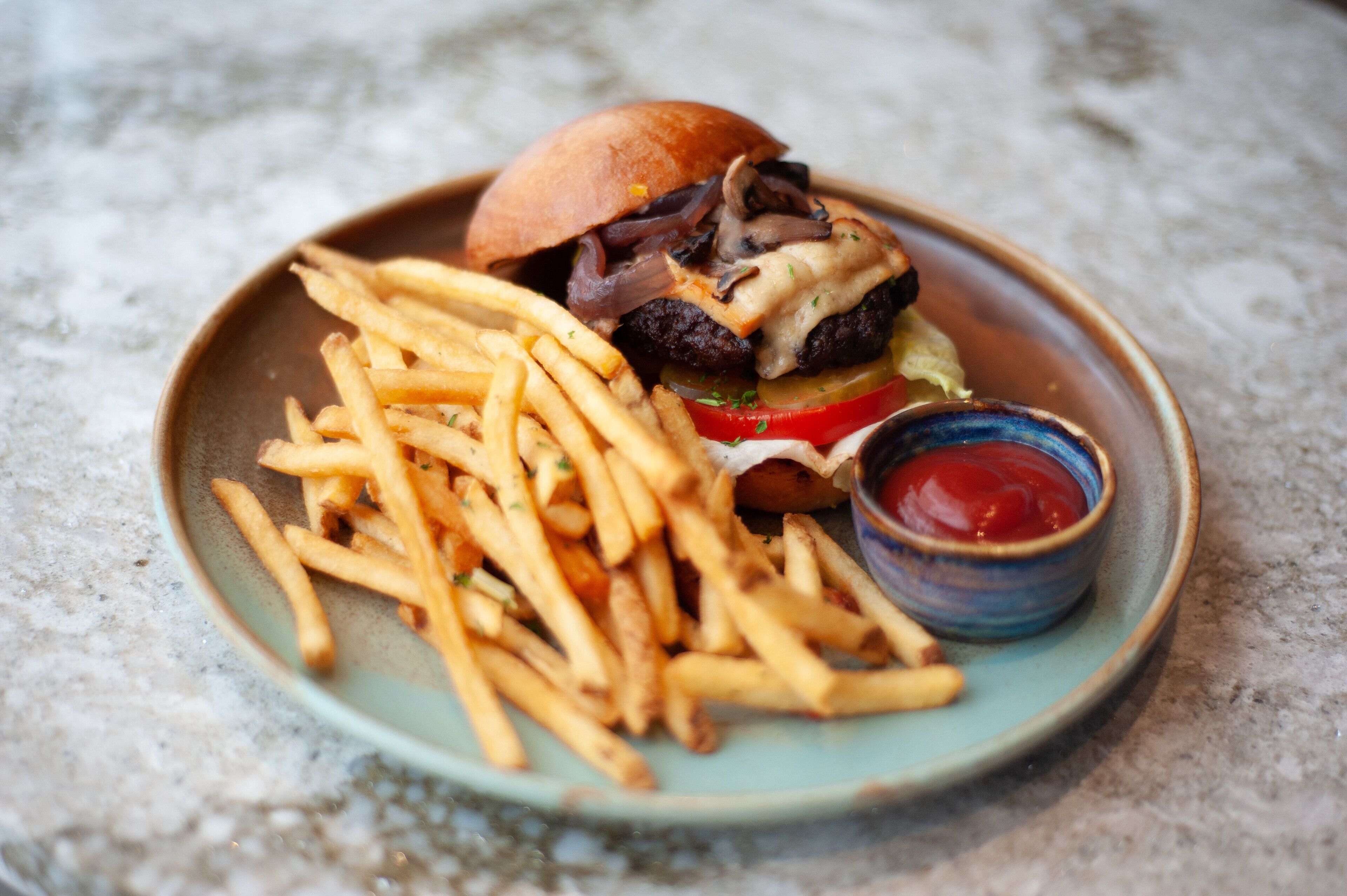 A plate with a burger, fries, and ketchup.
