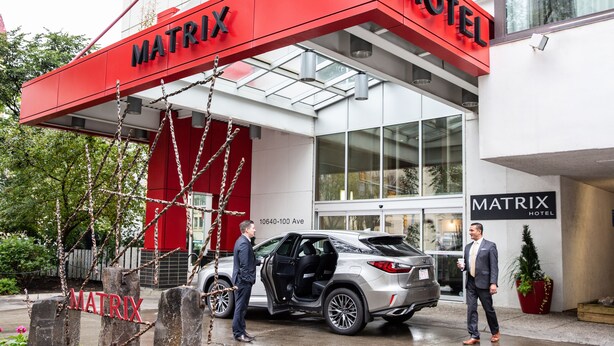 A modern hotel entrance with a prominent red awning and a glass facade.