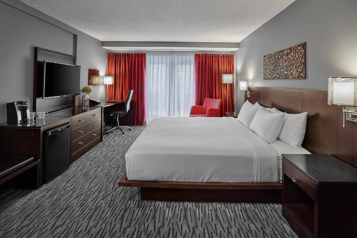 A hotel room with a large bed, a desk with a chair, a television, and a coffee maker.