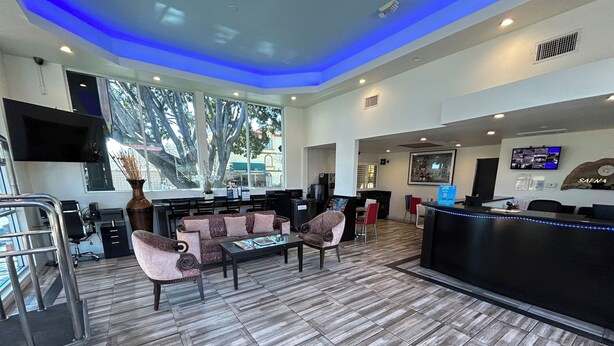 A modern hotel lobby with a reception desk, seating area, and large windows offering a view of the outdoors.