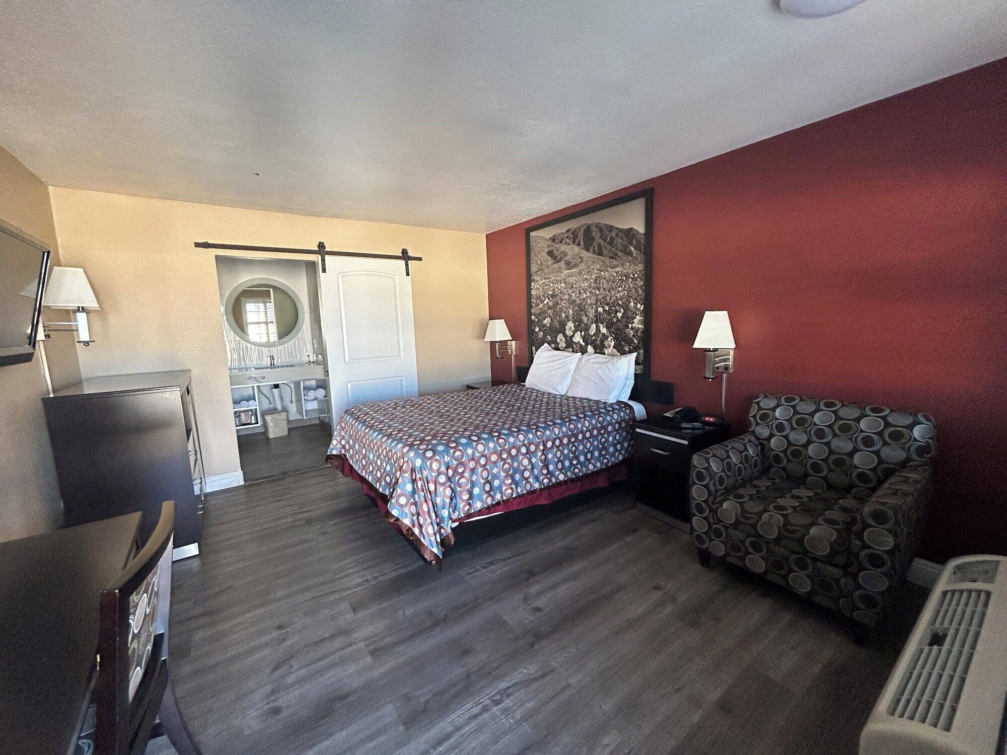A hotel room with a bed, a desk, a chair, and a large window.