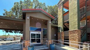 A motel with a red roof, a glass entrance, and a parking lot.
