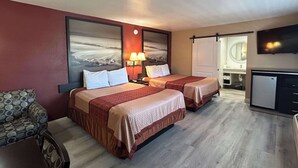 A hotel room with two beds, a sofa, a TV, and a desk.