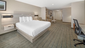 A hotel room with a large bed, a desk with a chair, a small table, and a kitchenette in the background. - Best Western Plus Twin View Inn & Suites (Redding)
