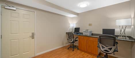 A small office with two desks, chairs, a printer, and a door.