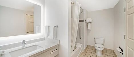 A bathroom with a large mirror, a sink, a toilet, and a shower.