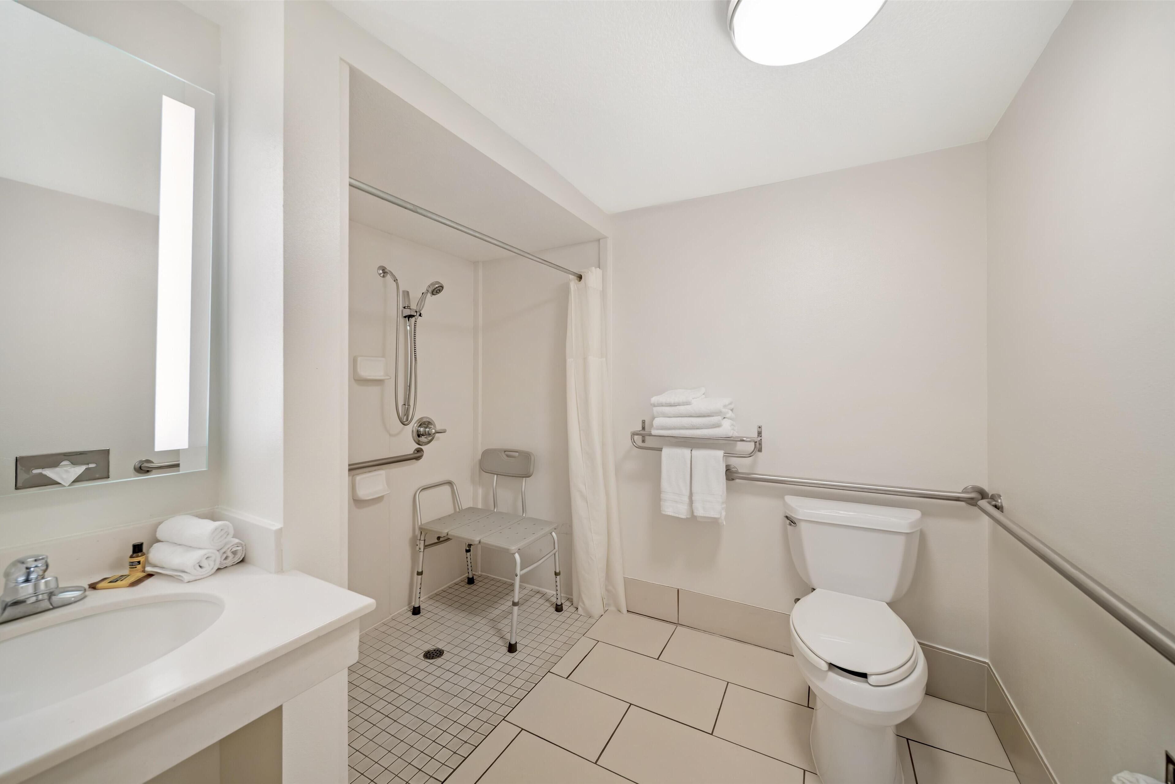 A modern bathroom with a white sink, toilet, and shower area.