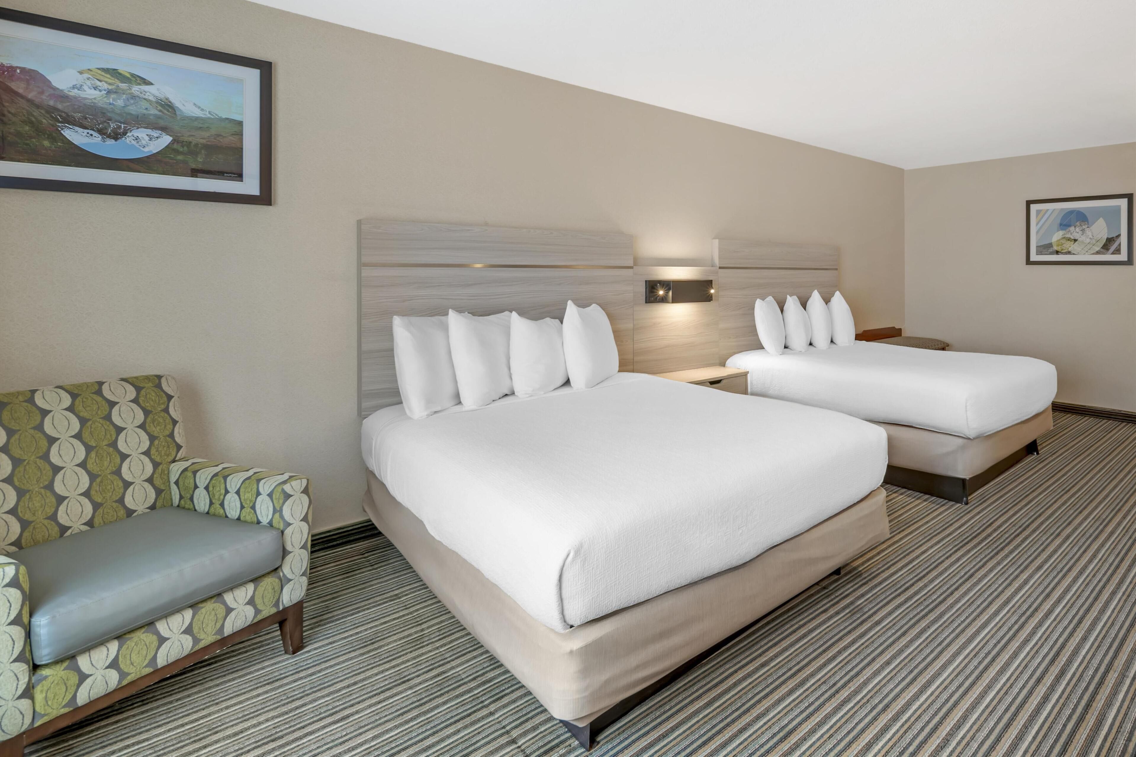 A hotel room with two beds, a sofa, and a painting on the wall.