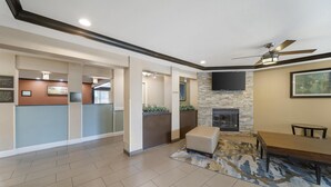 A spacious lobby with a fireplace, seating area, and a television mounted on the wall. - Best Western Plus Twin View Inn & Suites (Redding)