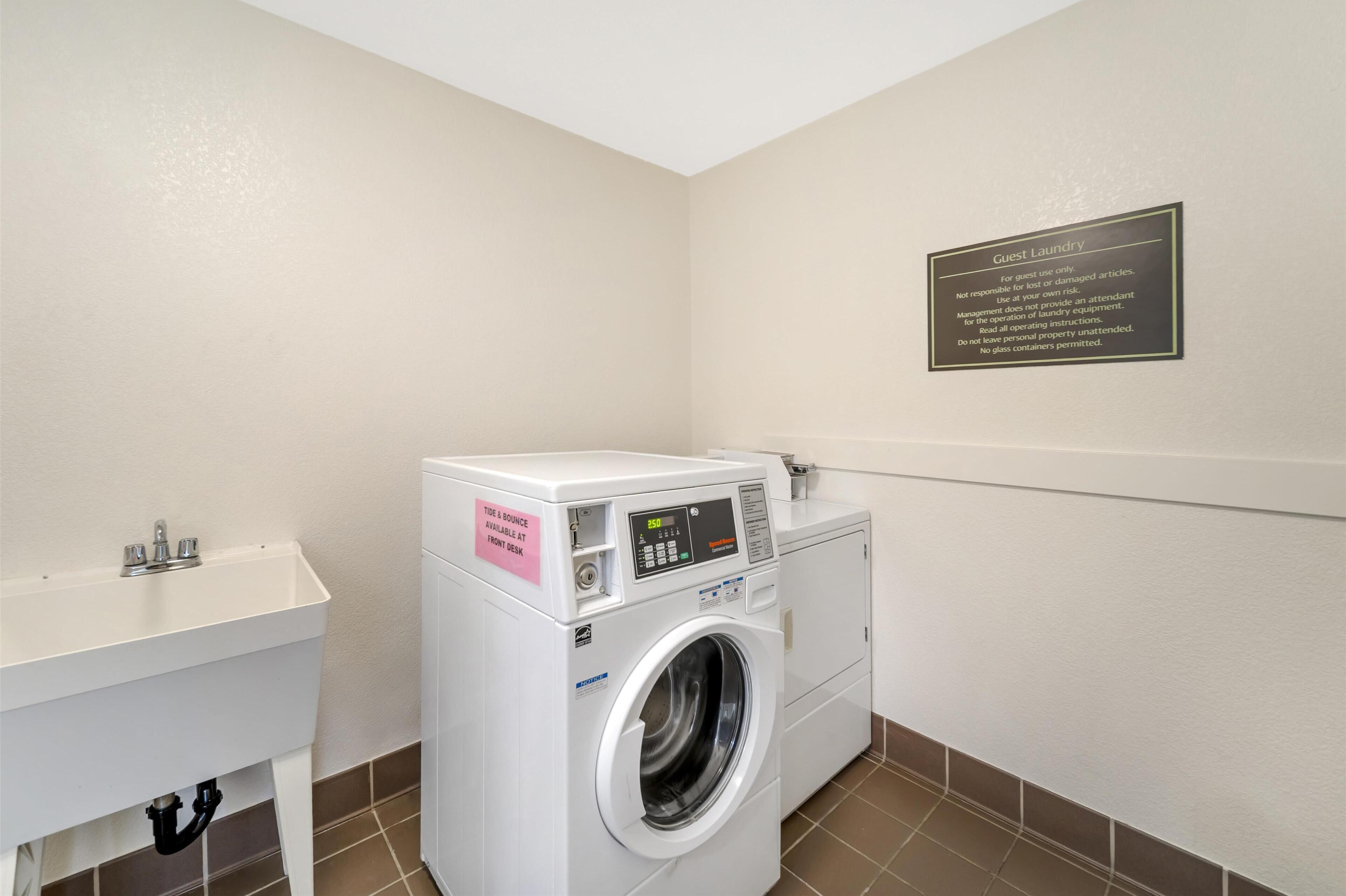A guest laundry area with a washing machine and a sink.