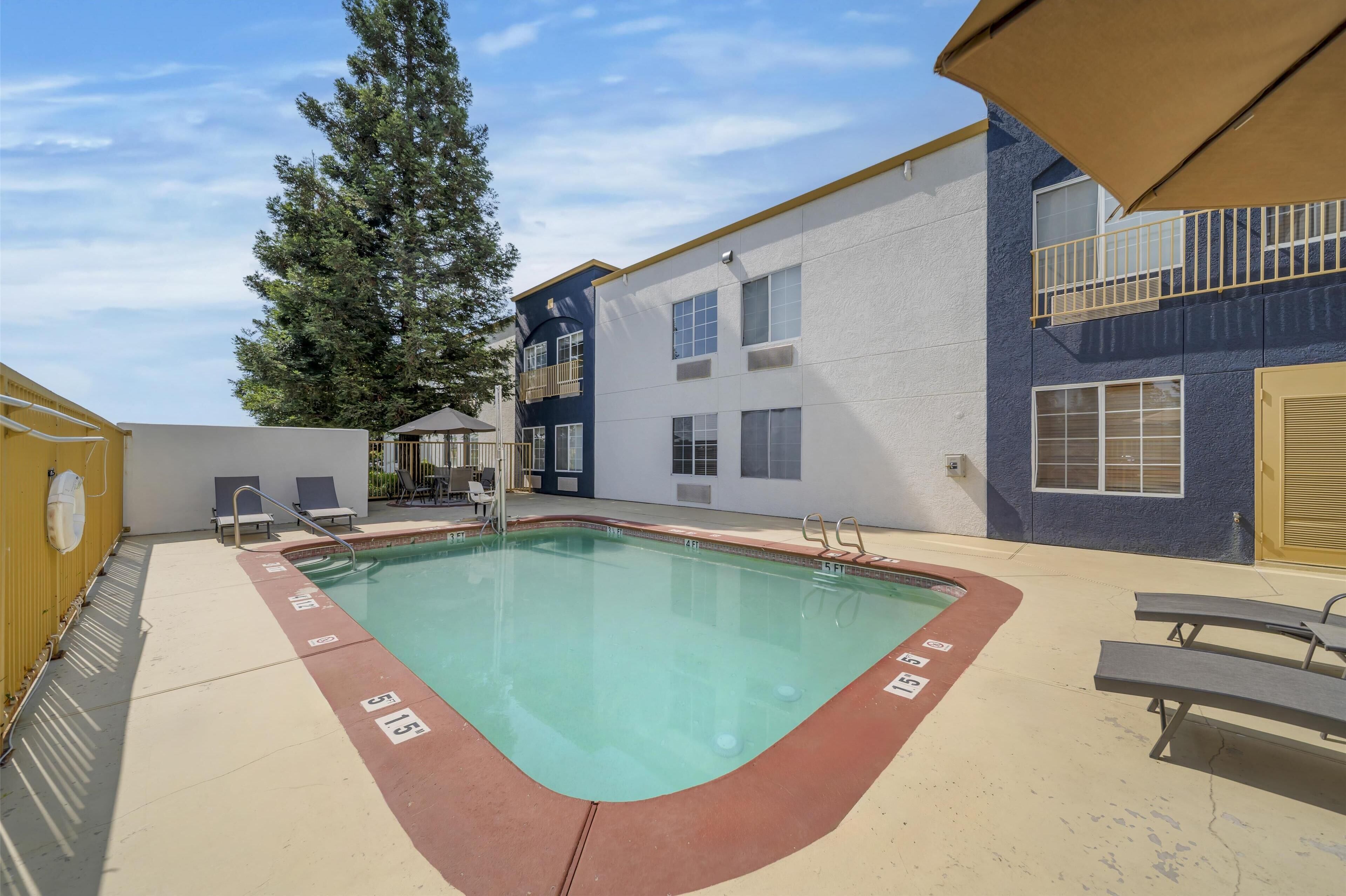 A swimming pool with a red border, surrounded by a building with a blue exterior and a yellow door.