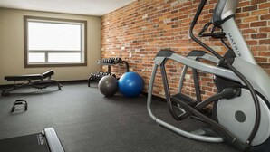 Een fitnessruimte met een hometrainer, gewichten en trainingsballen.