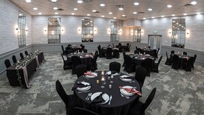 A conference room with multiple tables, black chairs, and white walls with mirrors. - Baymont by Wyndham Red Deer (Red Deer)