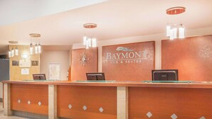 A reception desk with a Baymont Inn & Suites sign, a clock, and a framed picture on the wall. - Baymont by Wyndham Red Deer (Red Deer)