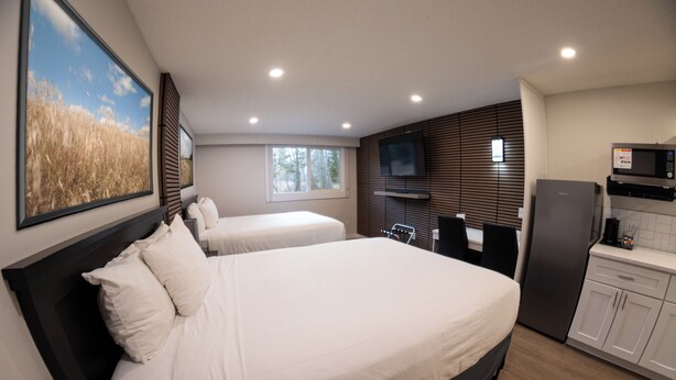 A bedroom with two beds, a TV, a microwave, and a refrigerator. - Baymont by Wyndham Red Deer (Red Deer)