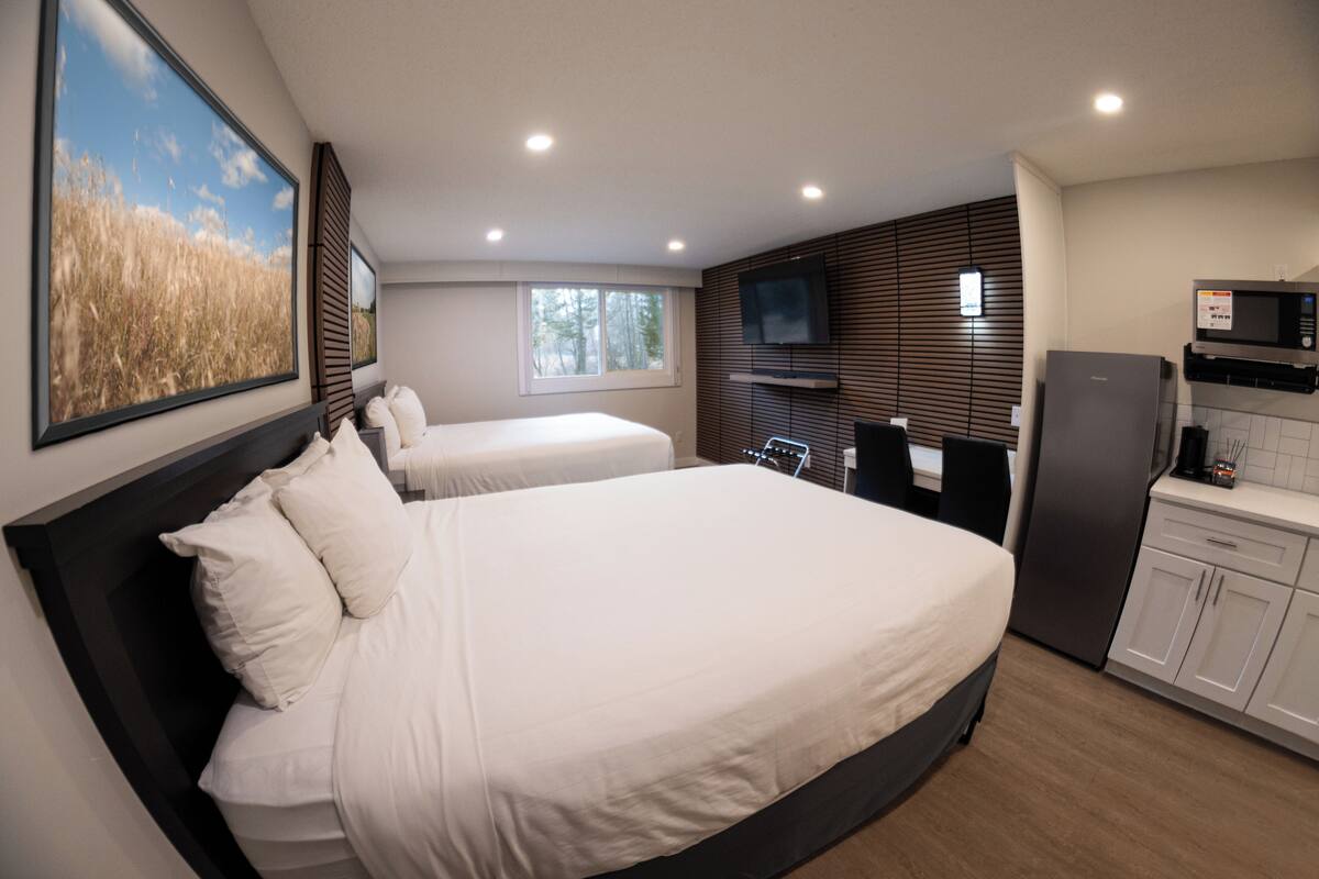 Ein Schlafzimmer mit zwei Betten, einem Fernseher, einer Mikrowelle und einem Kühlschrank.