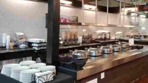 A buffet setup with multiple serving stations, a variety of food containers, and a table with stacked plates. - Baymont by Wyndham Red Deer (Red Deer)