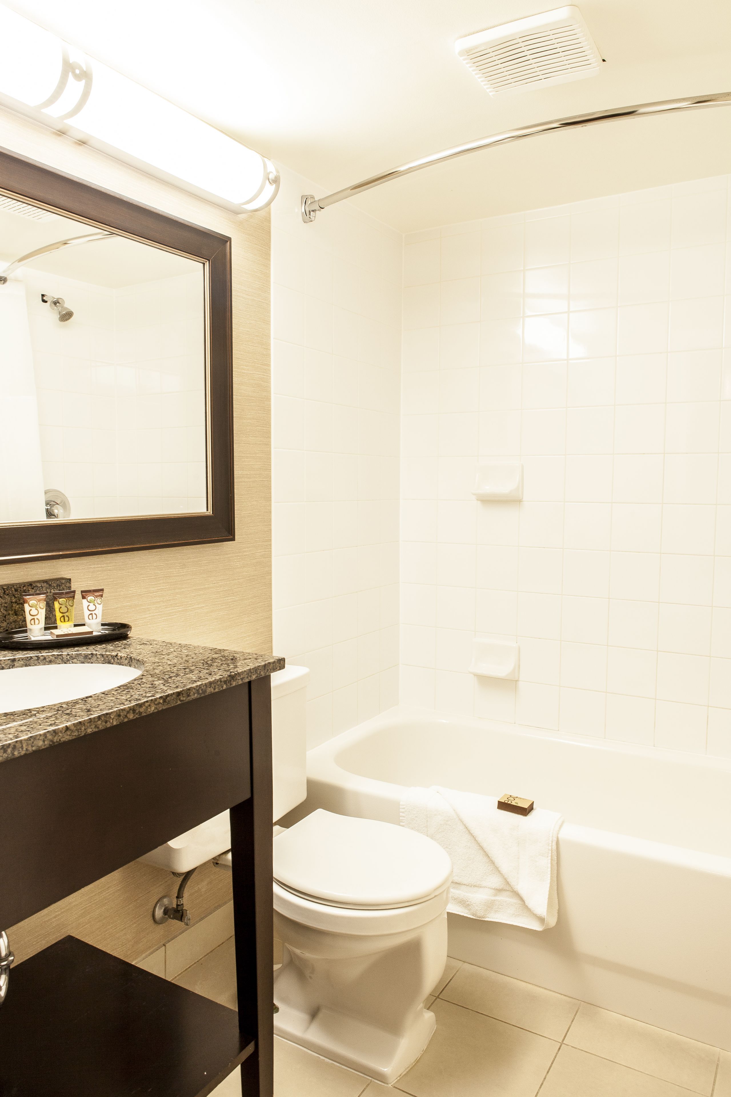 A bathroom with a white toilet, a bathtub, and a sink with a mirror above it.