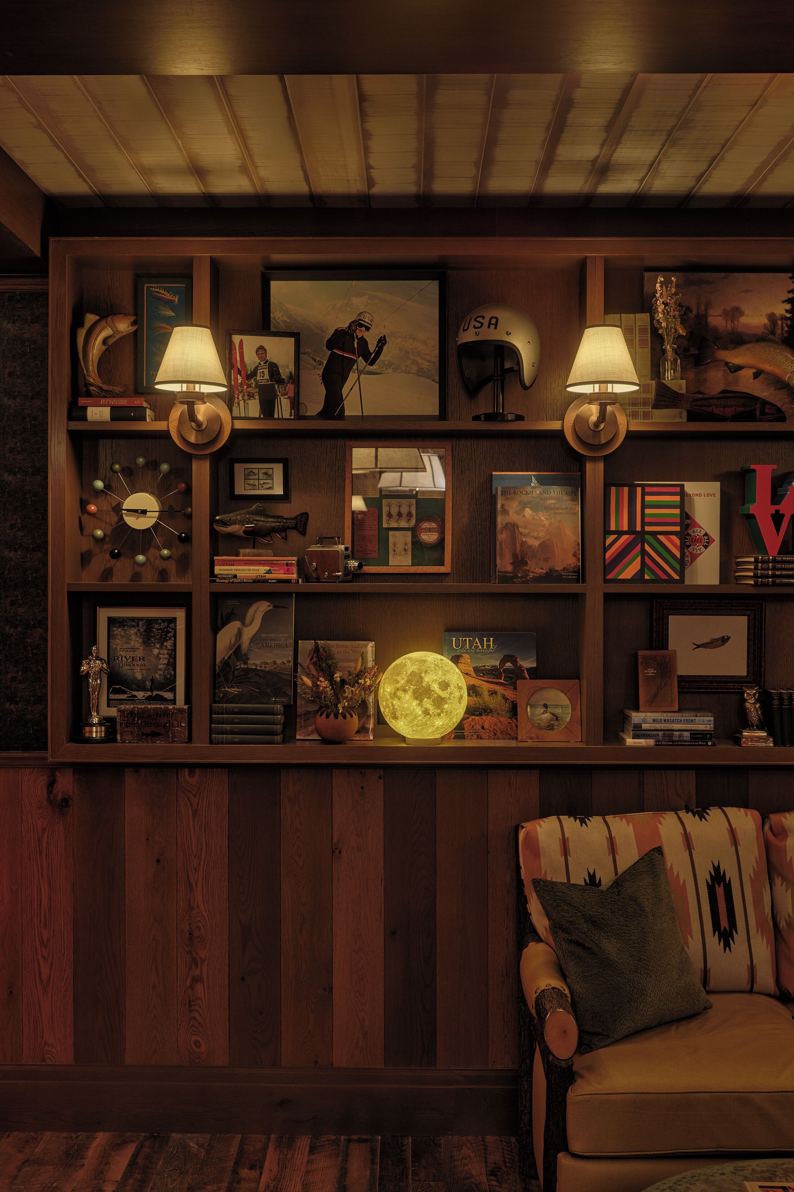 Een gezellige kamer met een houten boekenkast, een lamp en een bank met een decoratief kussen.
