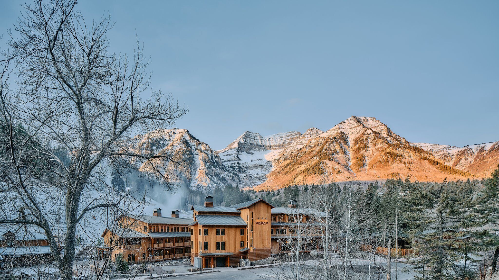 A lodge with a wooden exterior, multiple stories, and a prominent mountain backdrop.