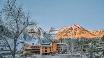 A lodge with a wooden exterior, multiple stories, and a prominent mountain backdrop.