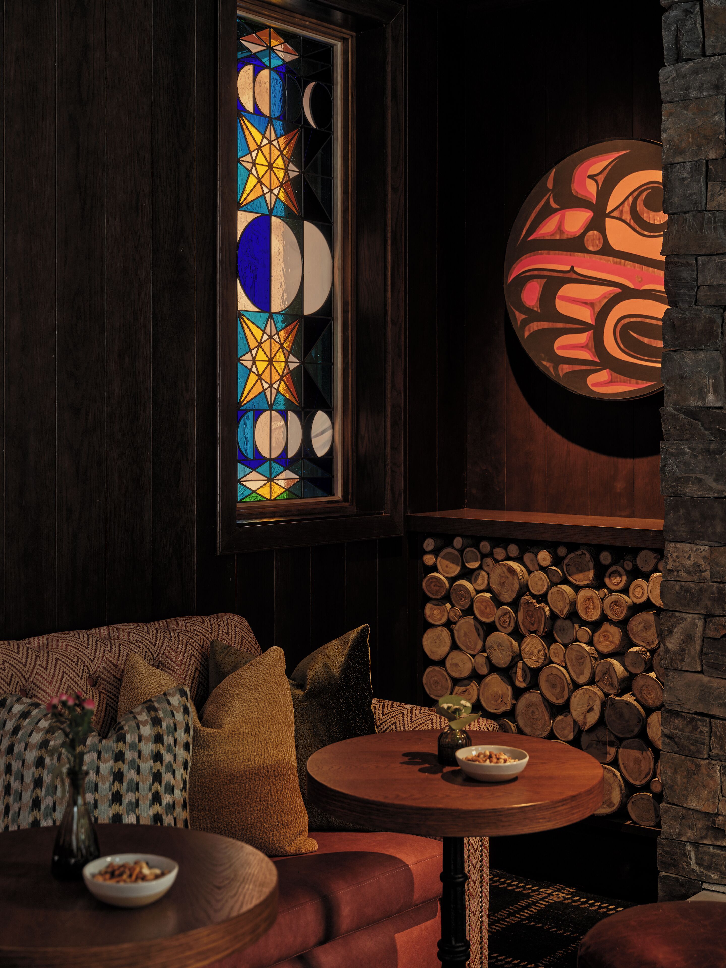 Una habitación acogedora con una pared de madera, una mesa redonda con un cuenco y un sofá con cojines estampados.