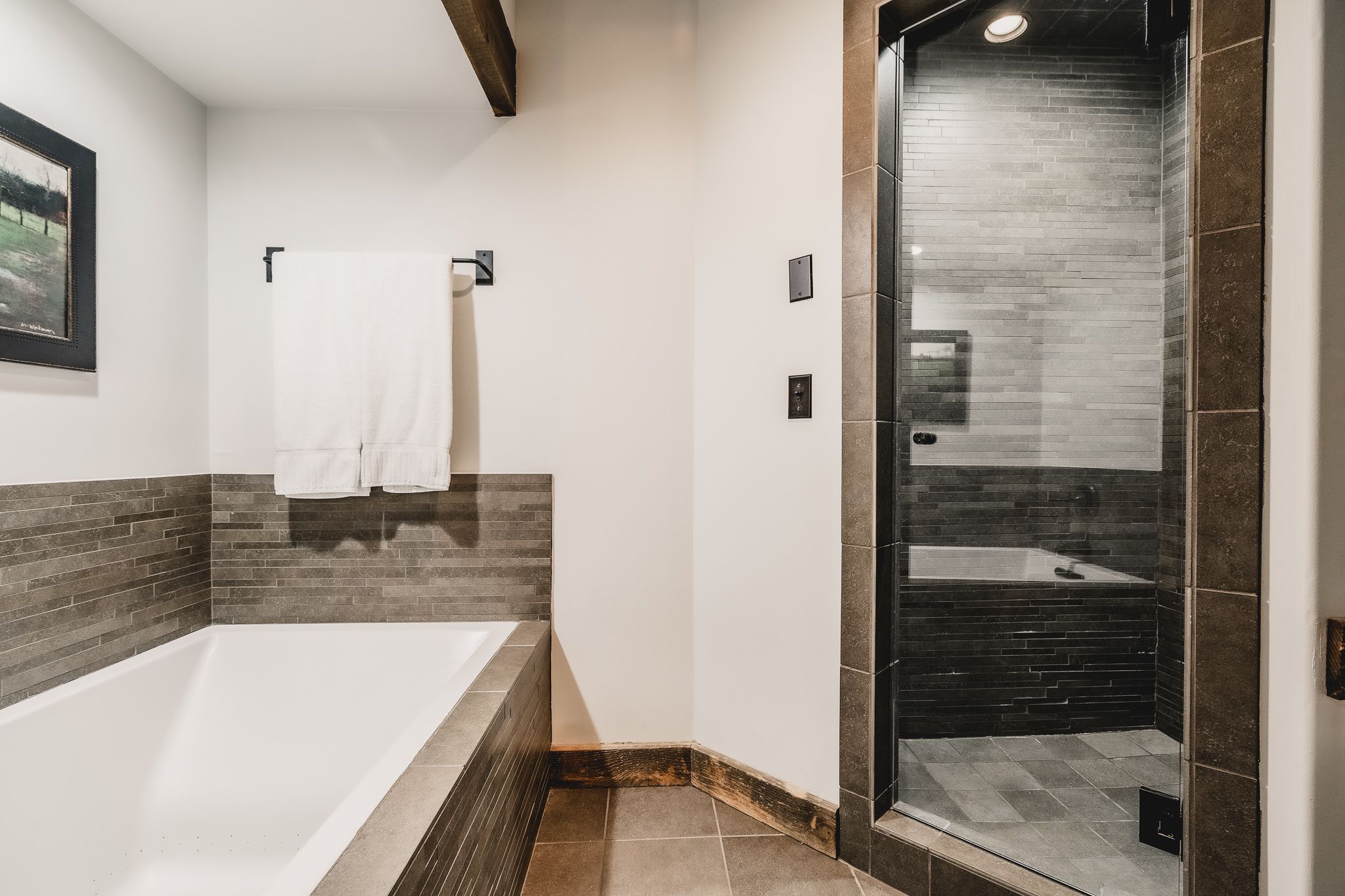A modern bathroom with a large bathtub, a glass-enclosed shower, and a tiled shower area.