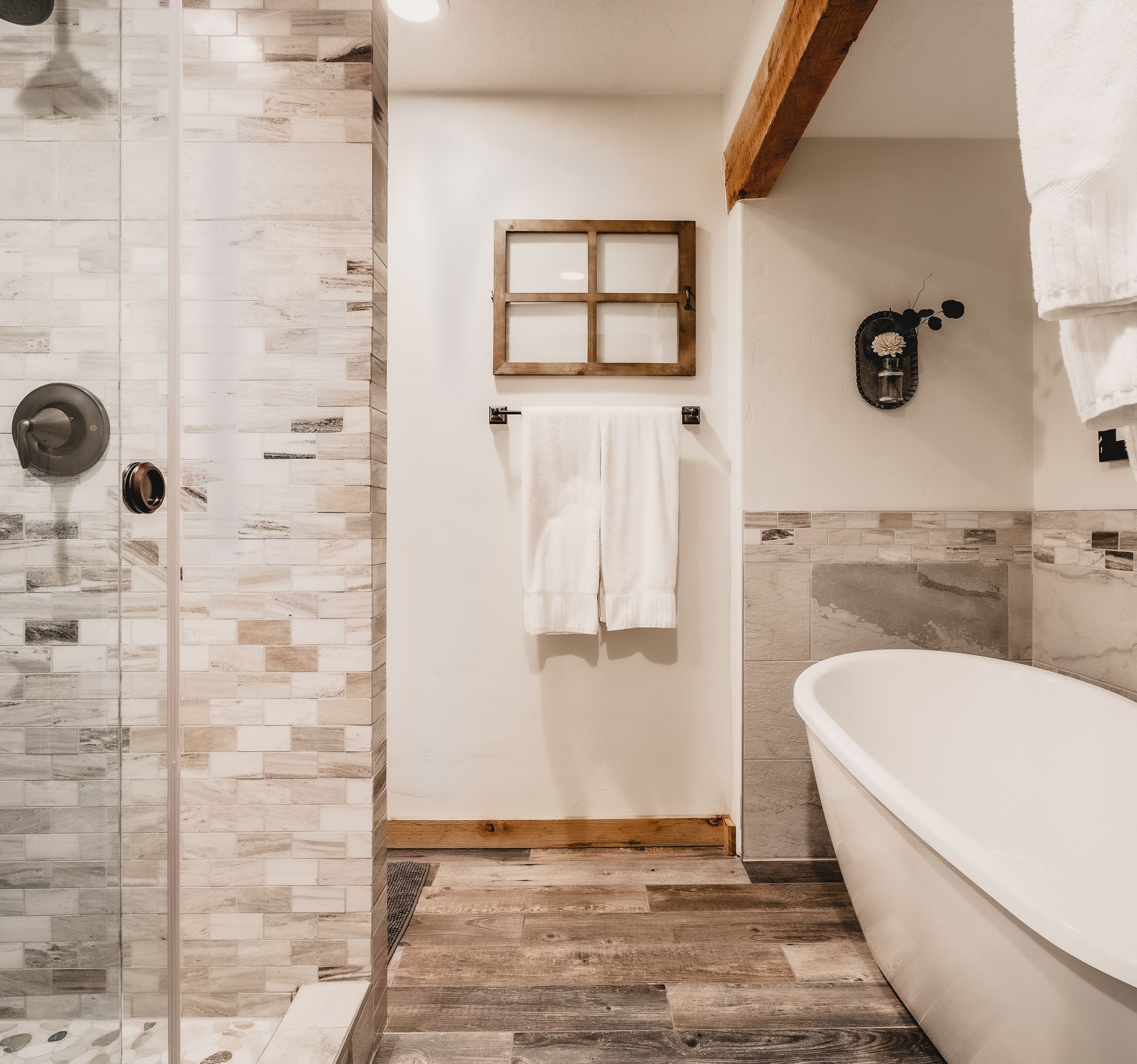 Un baño con ducha, bañera y suelo de madera.