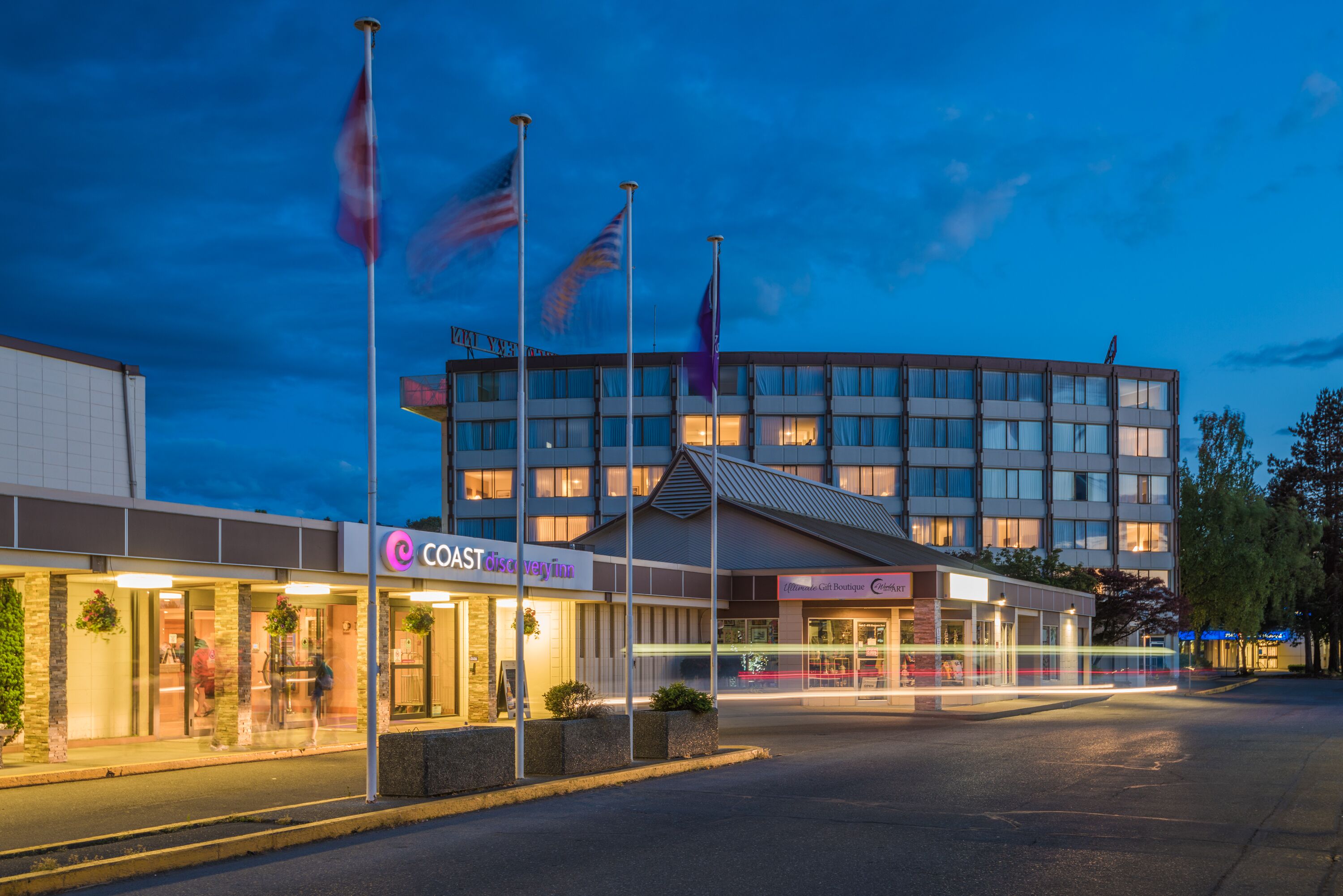 Ein Hotel mit modernem Design, das eine große Glasfassade und mehrere Flaggen zeigt.
