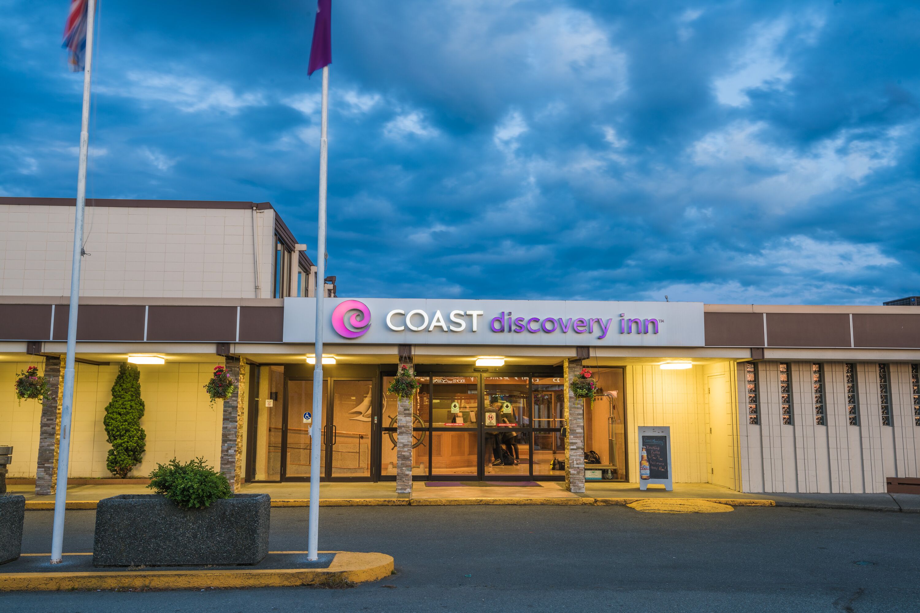 The exterior of a Coast Discovery Inn with a clear sky and a well-lit entrance.