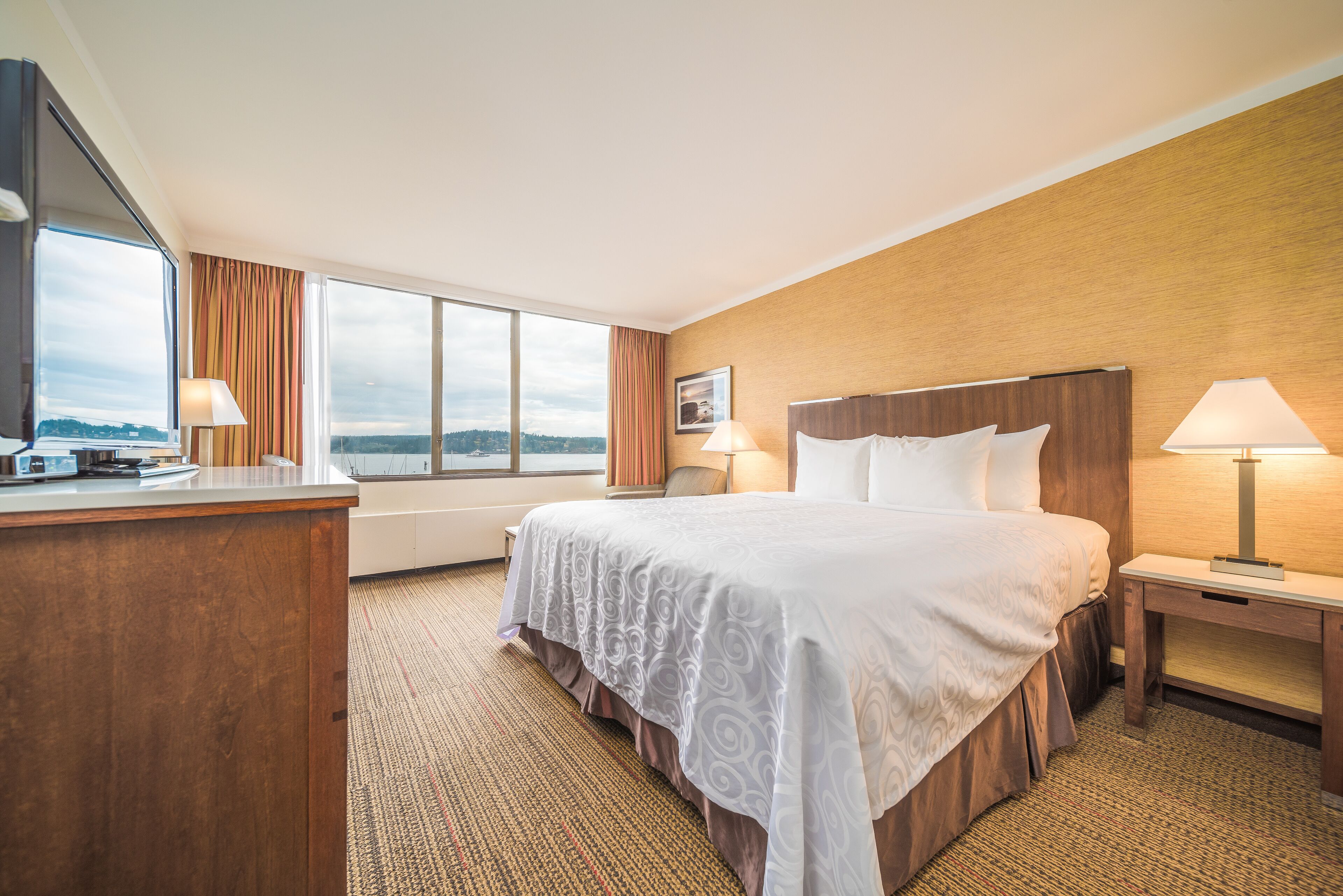 Quarto de hotel com uma cama grande, uma mesa, uma cadeira e uma janela com vista para o exterior.
