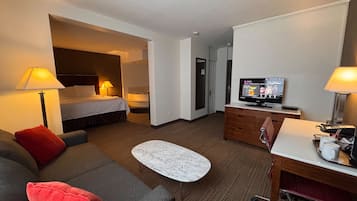Une chambre d’hôtel comprenant un lit, un canapé, un bureau, une télévision et une salle de bain.