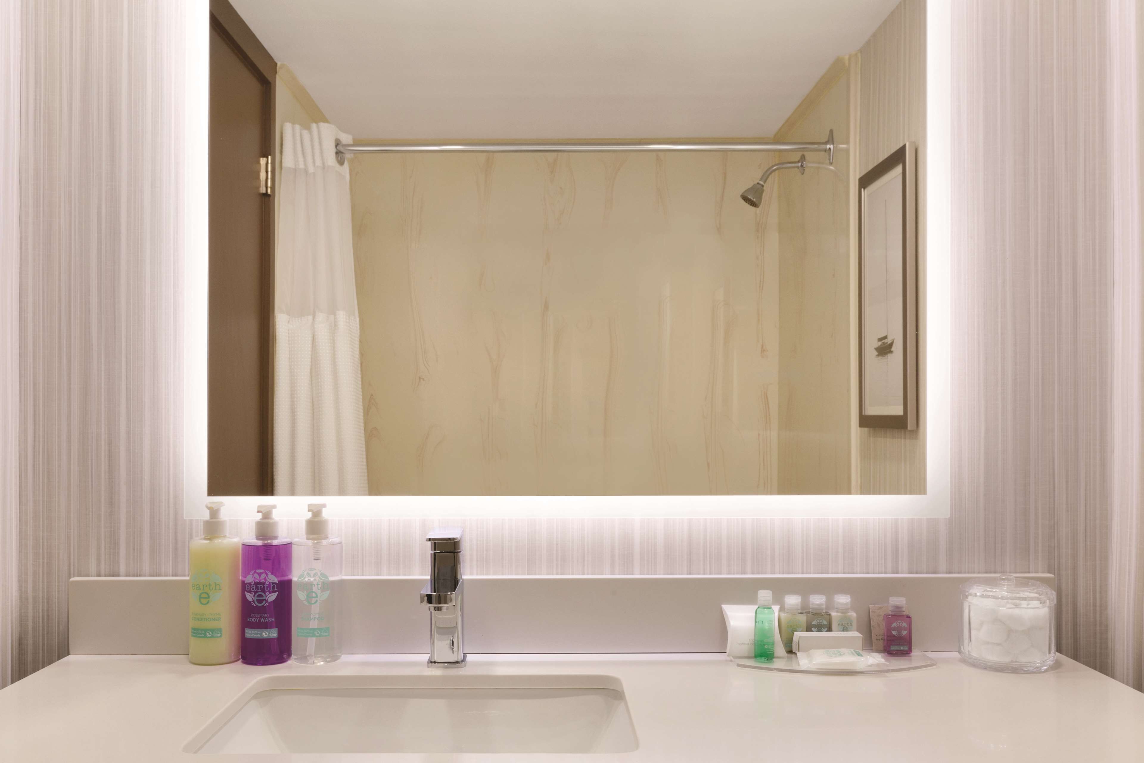 A bathroom with a large mirror, a sink, and various toiletries on the counter.