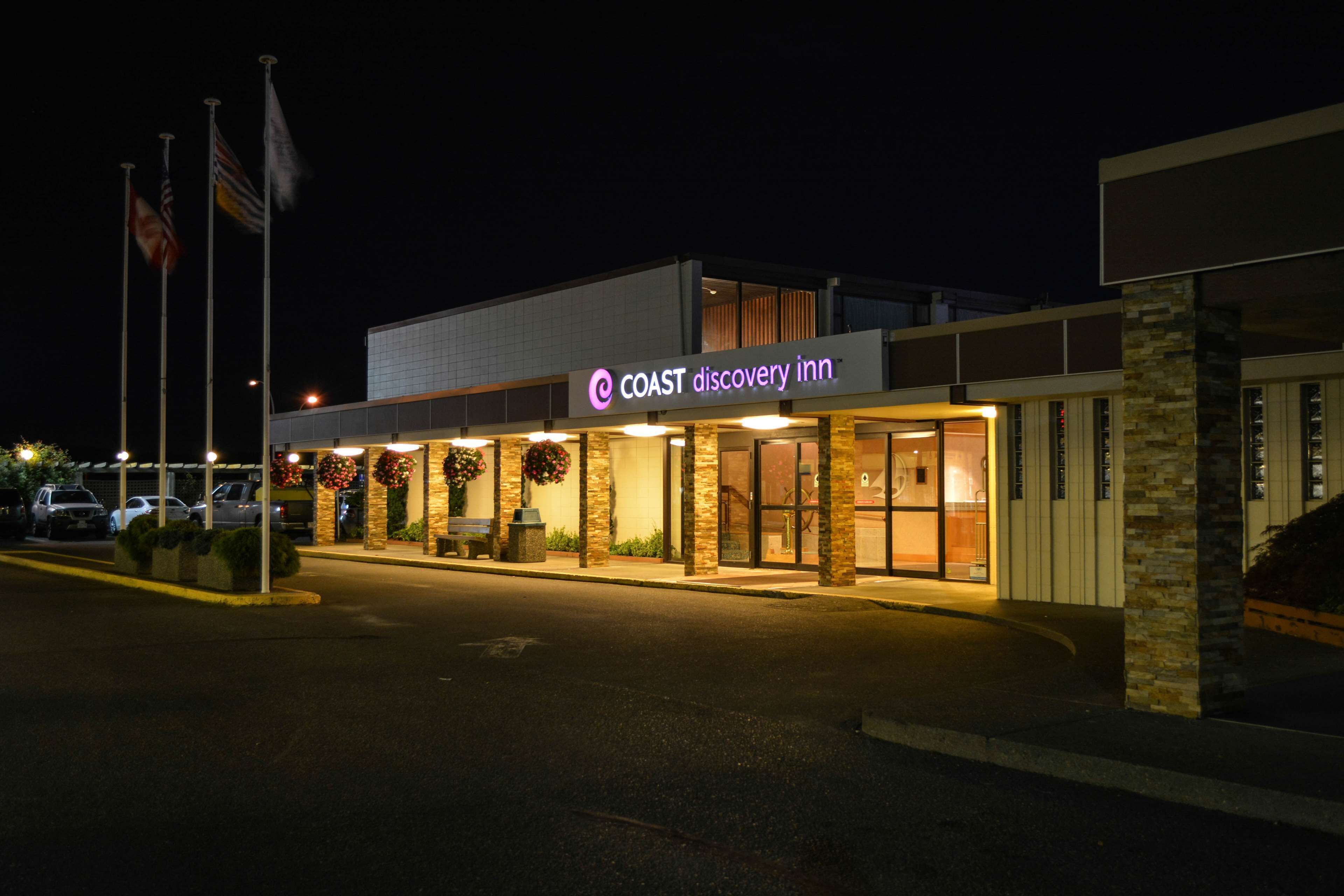 Een modern gebouw met een bord met de tekst 'COAST Discovery Inn' bij nacht.