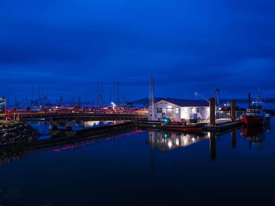 A marina at dusk with calm water reflecting the lights.