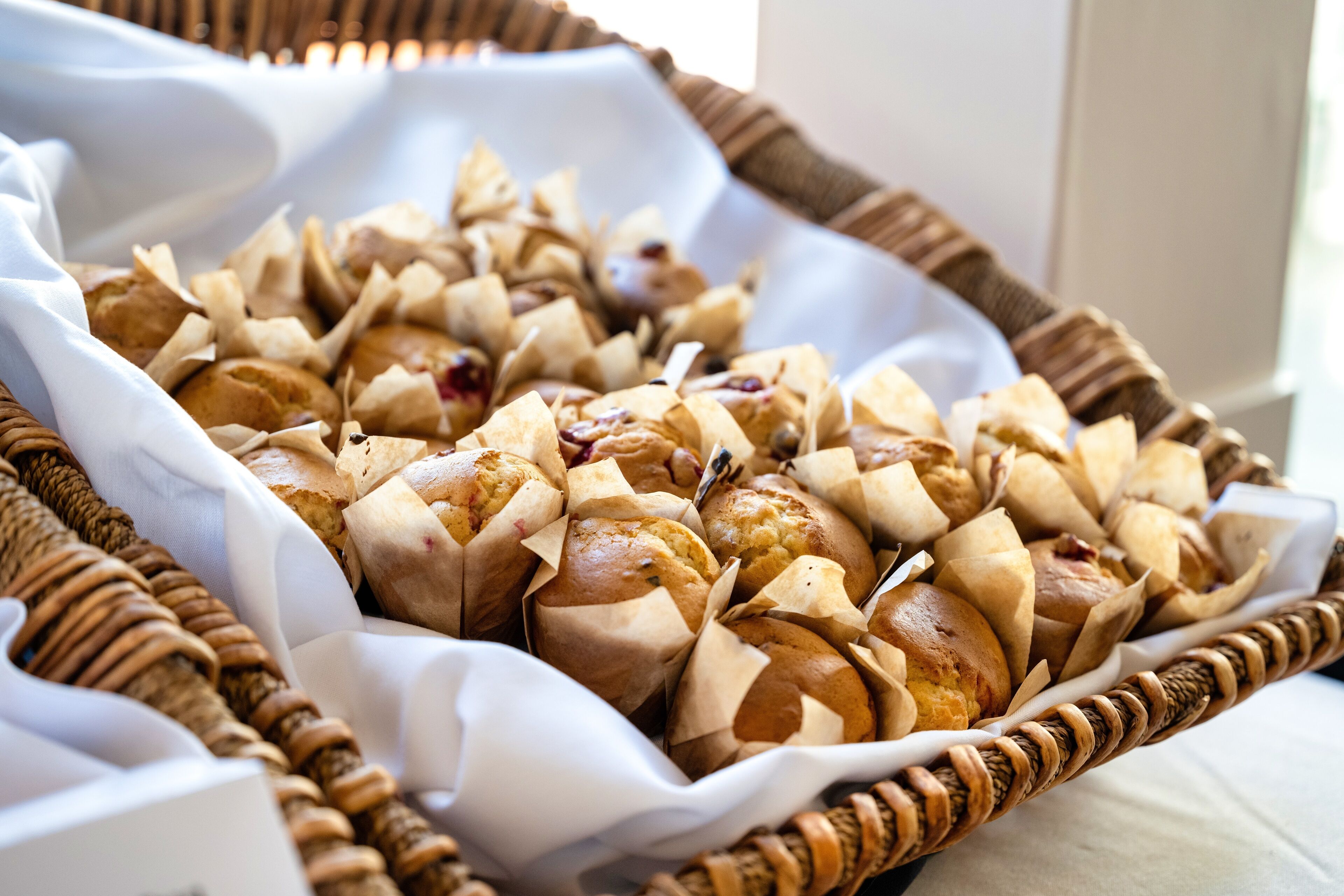 A basket filled with various baked goods, possibly pastries, wrapped in paper.